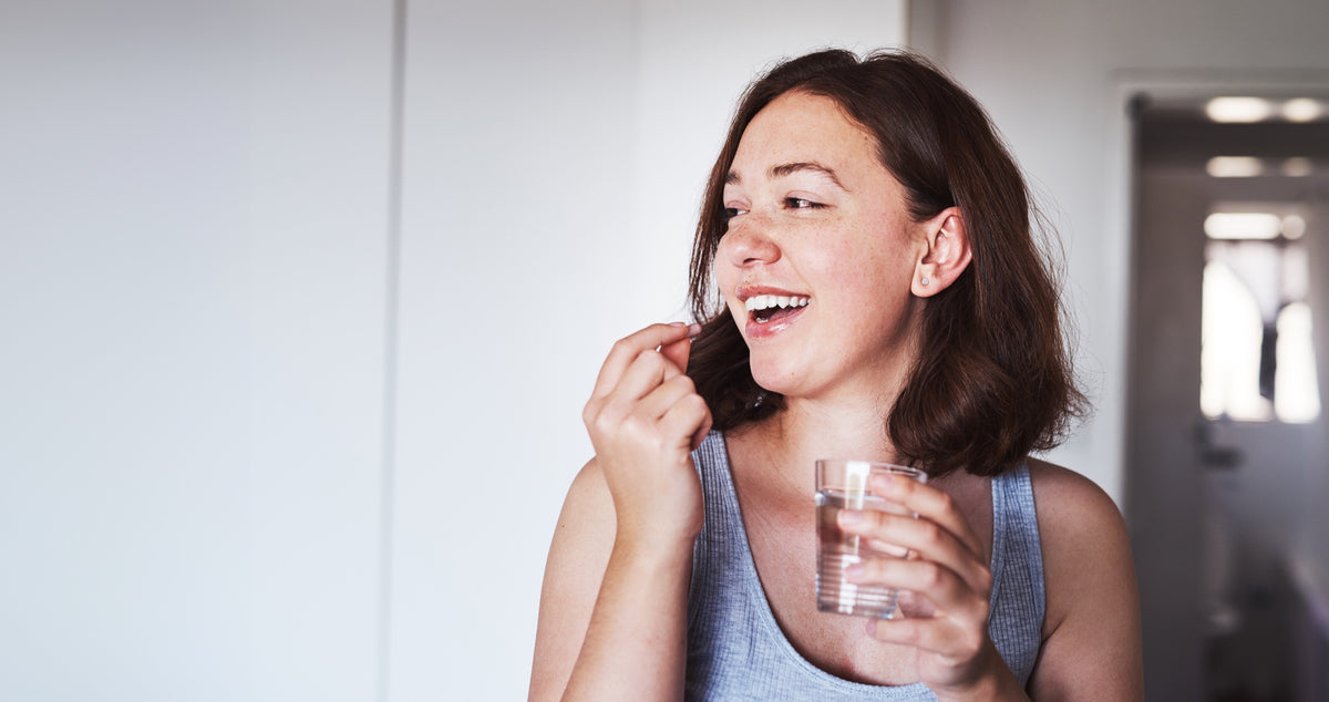 Lachende vrouw die een U-BLISS capsule neemt